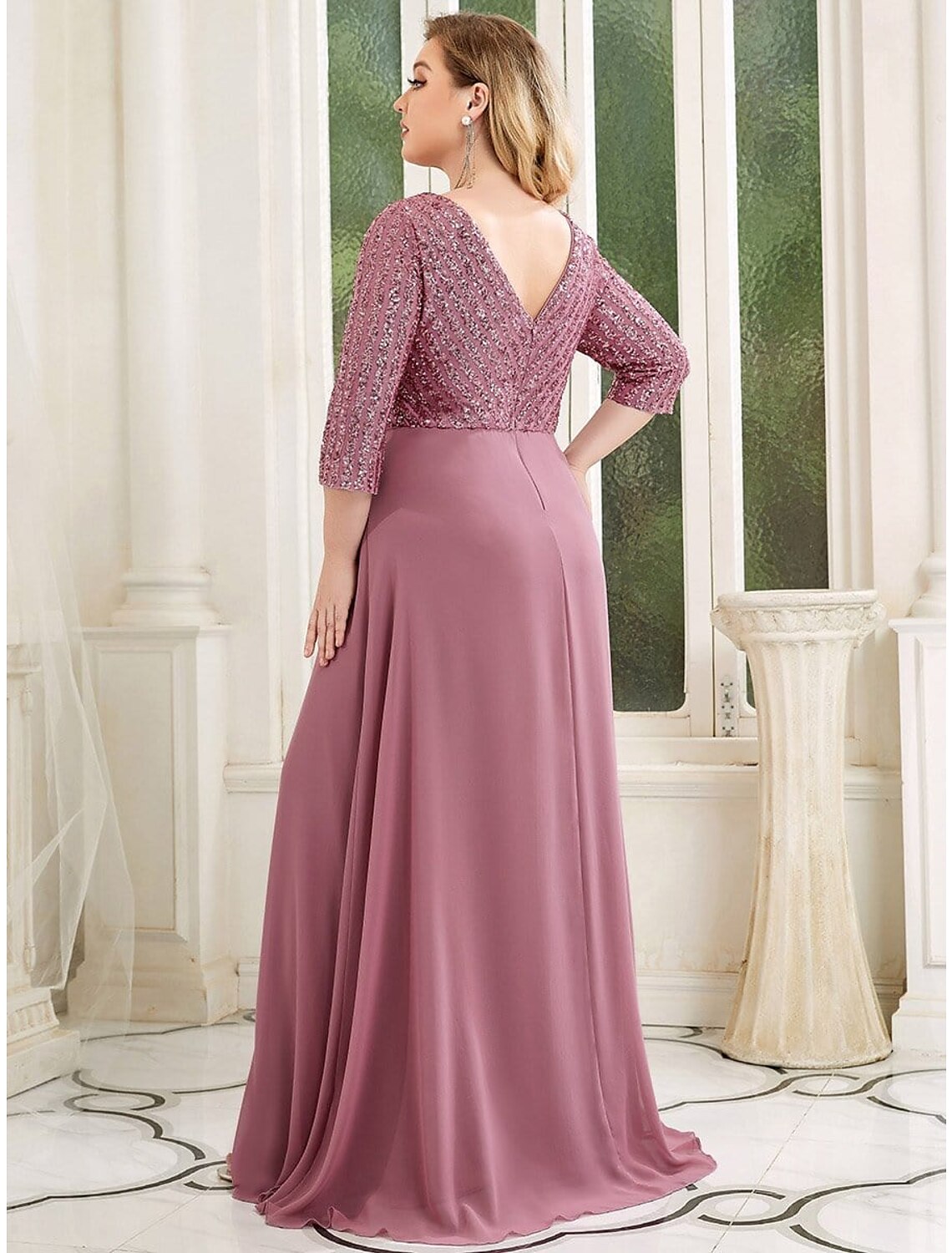 Side view of a woman in a dark A-line sequin chiffon gown.
