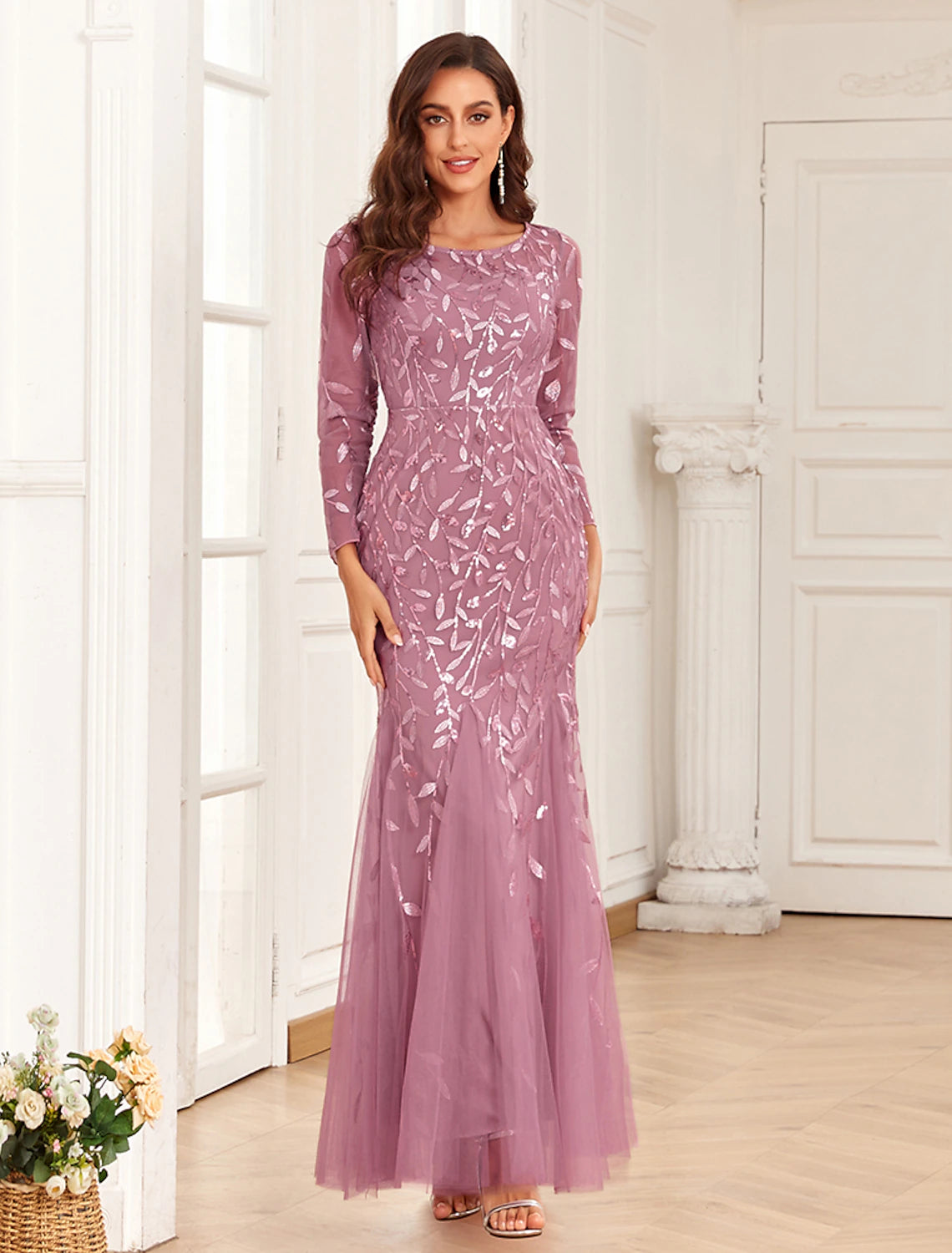Woman wearing a long sleeve jewel neck mermaid evening gown with tulle embroidery.