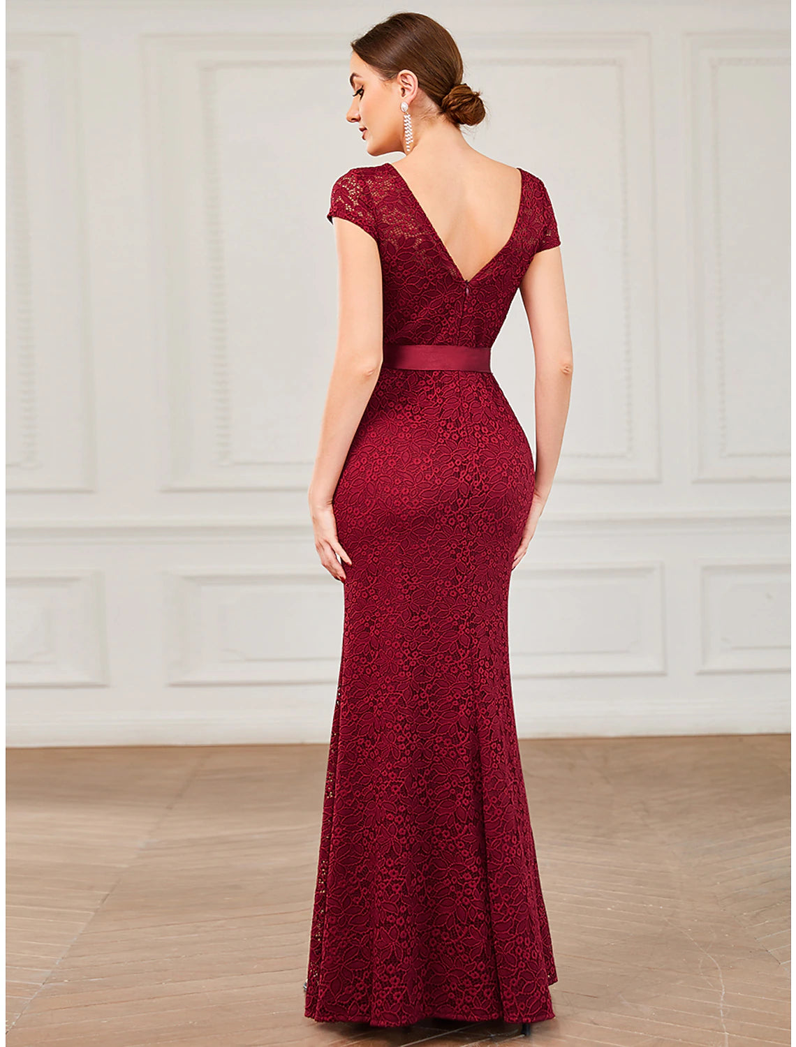 Side view of a woman in a dark mermaid trumpet evening gown, showcasing the floor-length silhouette.