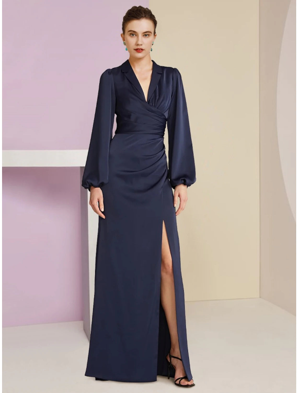 Woman wearing a dark elegant V-neck long sleeve sheath dress with ruching and a split front.