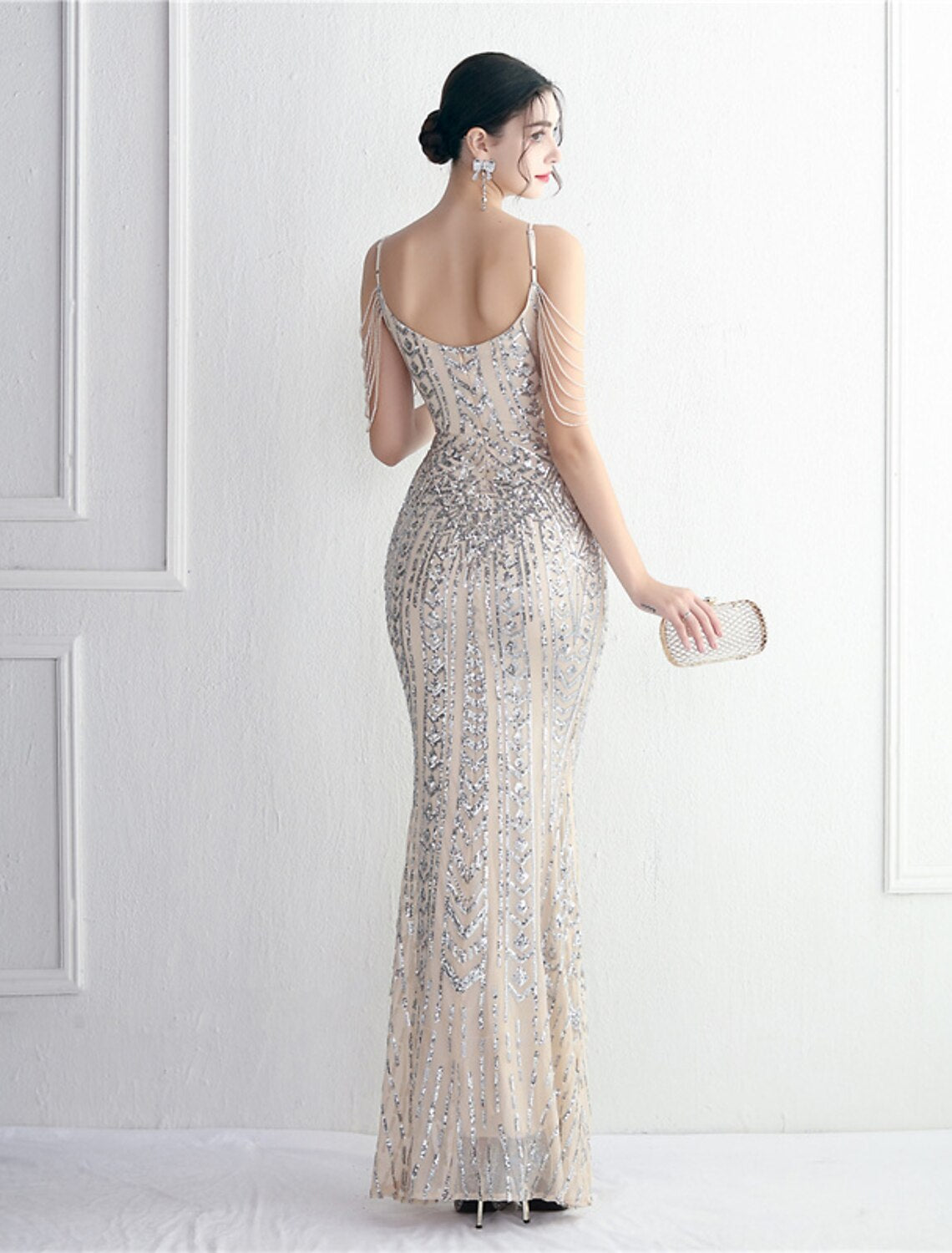 Woman posing in a sparkling mermaid trumpet evening gown, side view.