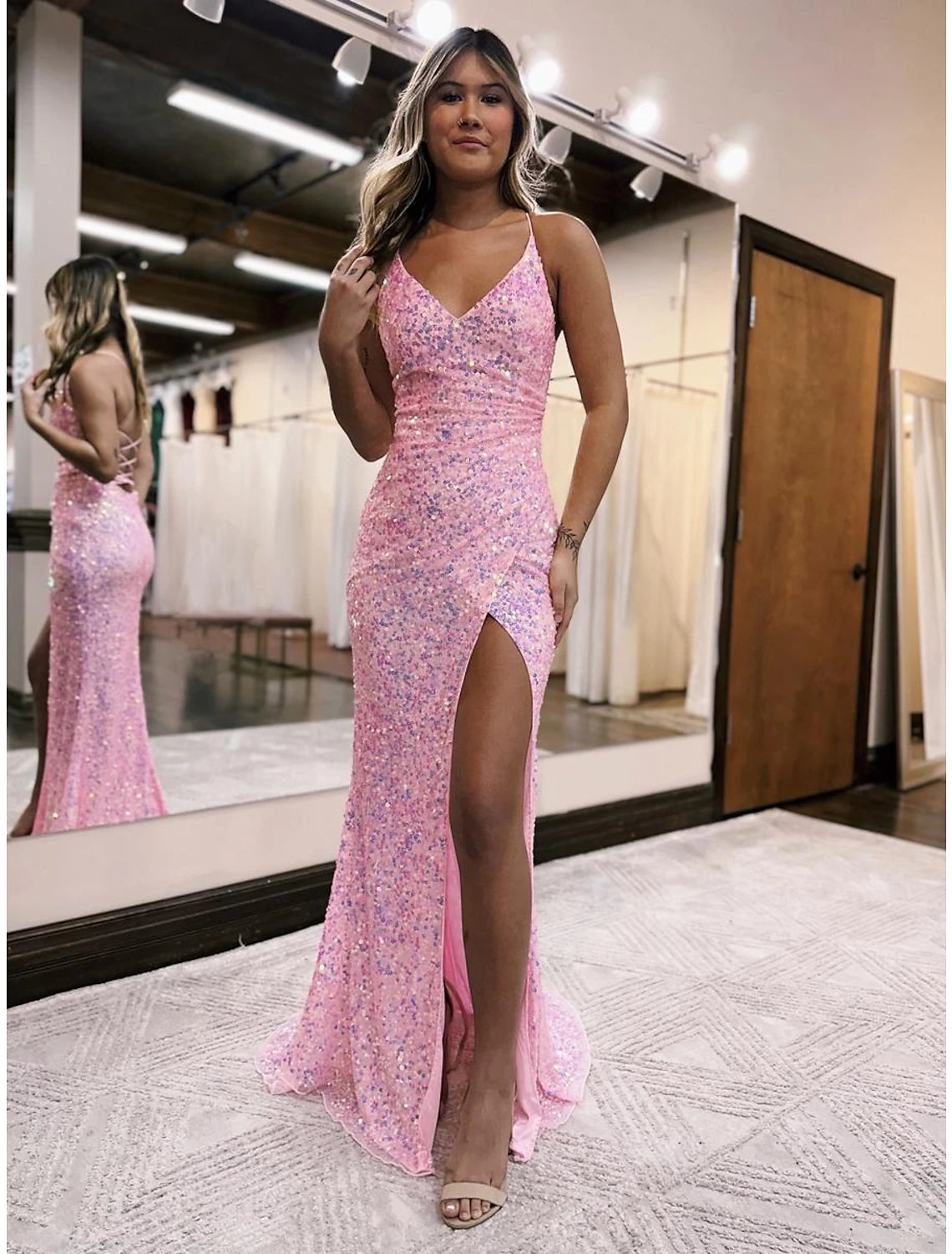 Woman wearing a sparkling V-neck mermaid prom dress with a high slit and sweep train.