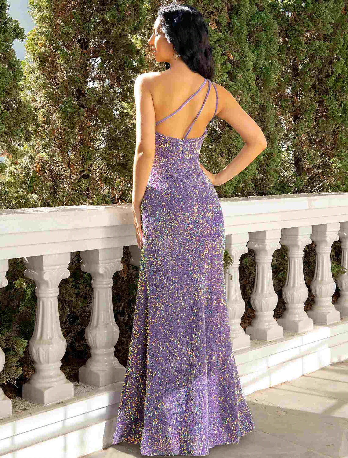 Back view of a model wearing a floor-length sequined one-shoulder gown.